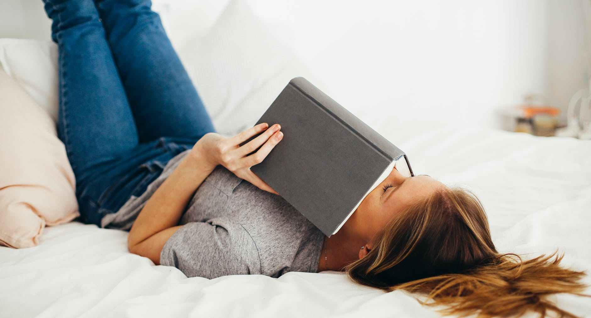 woman lying on bed holding book